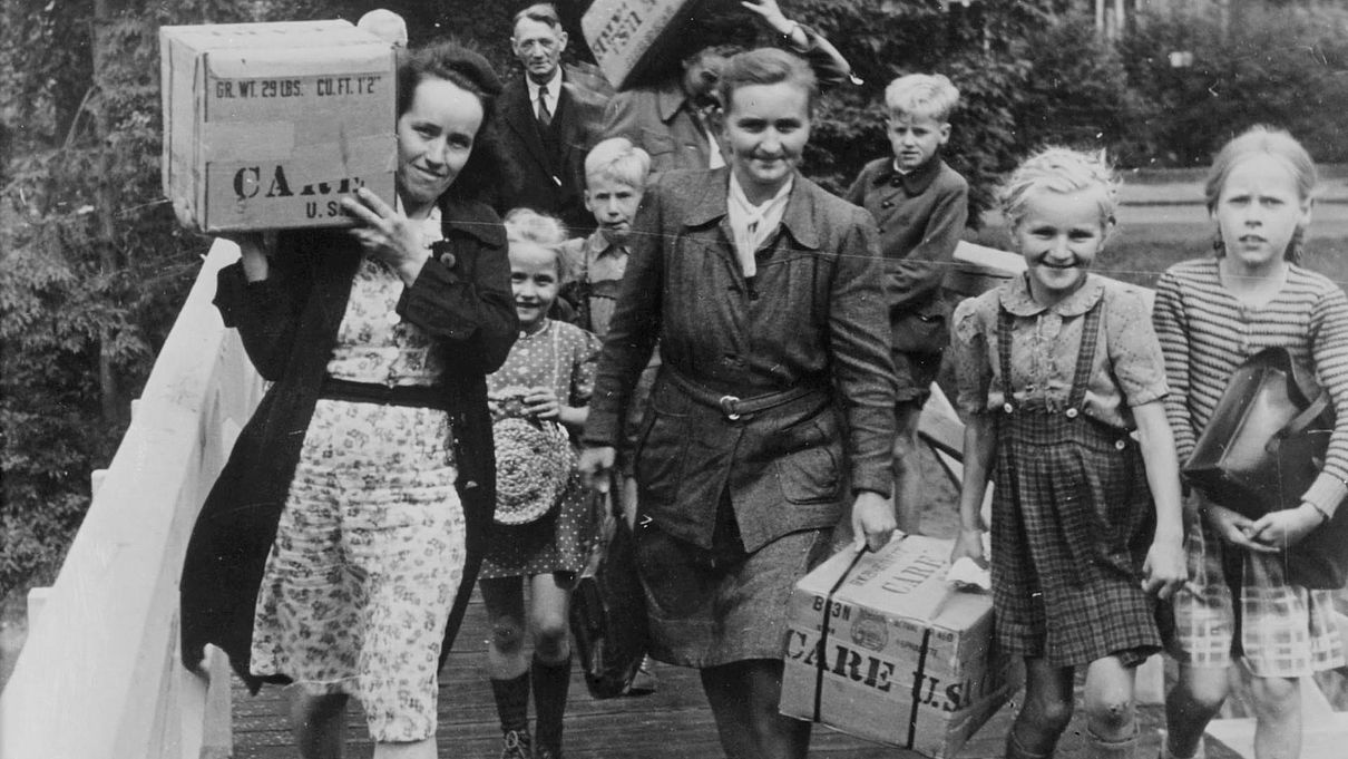 Frauen im Nachkriegsdeutschland tragen CARE-Pakete
