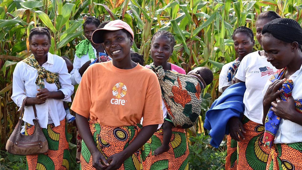 Frauen stehen lachend vor einem Maisfeld.