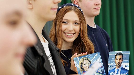 Schuelerin mit Planspielkarte Eine Schuelerin haelt eine Spielkarte des Planspiels in die Kamera