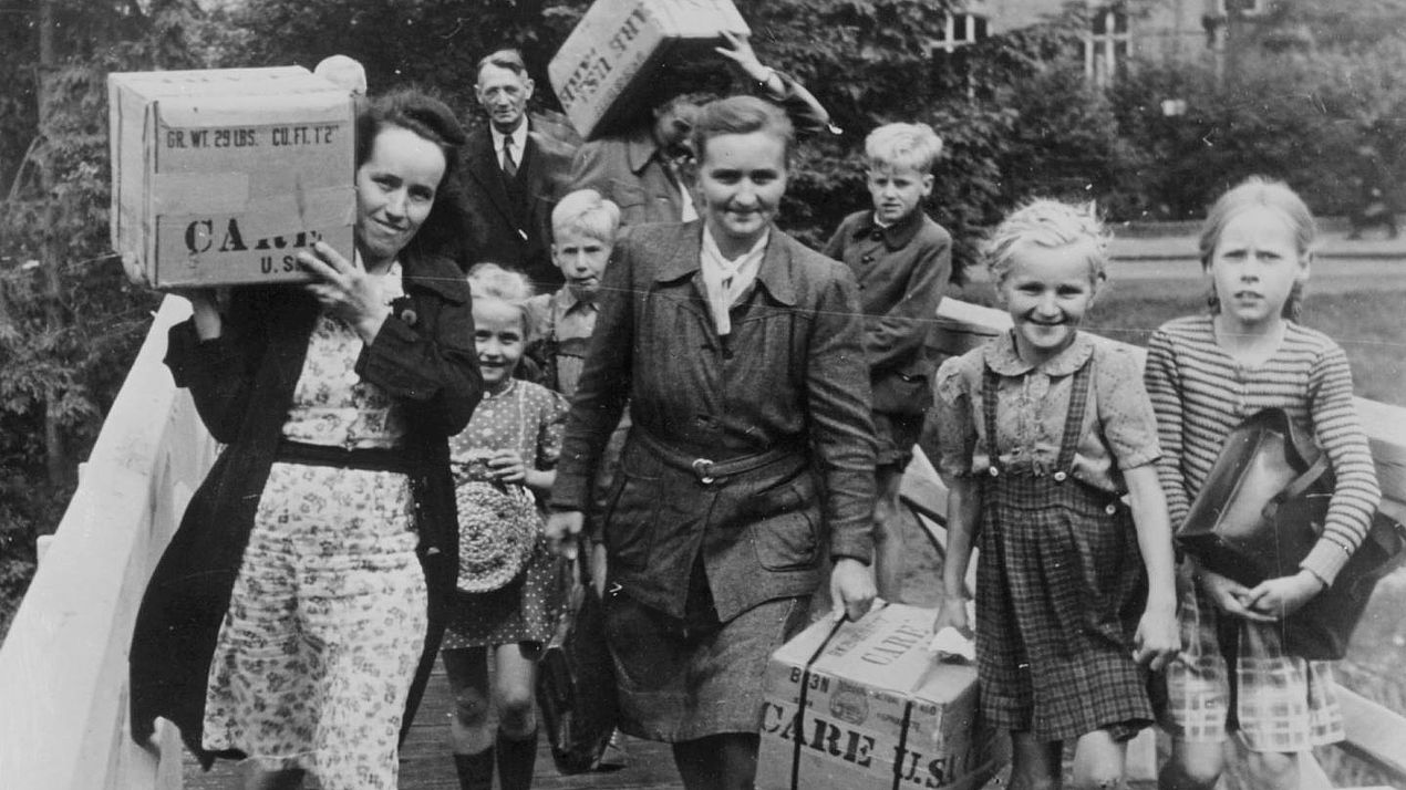 Frauen und Kinder mit CARE-Paketen Frauen und Kinder tragen CARE-Pakete.