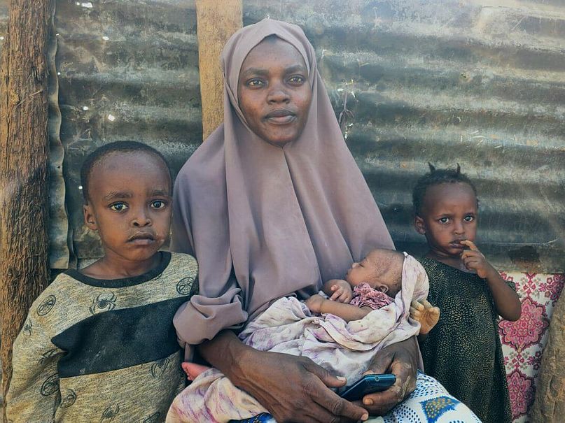 Khadra mit drei ihrer Kinder Khadra sitzt mit drei ihrer Kinder vor ihrer Unterkunft.