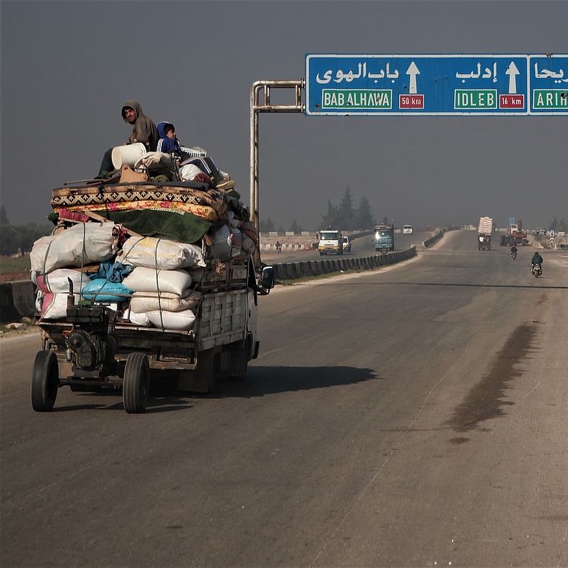 Zivilisten fliegen auf einem vollbepackten Wagen vor der Gewalt in Idlib