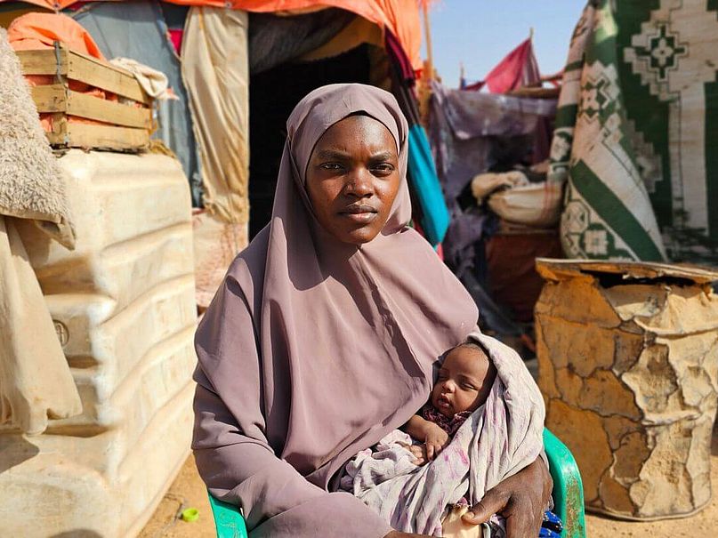 Khadra hält Bushra auf dem Arm Khadra sitzt und hält ihr Baby Bushra auf dem Arm.
