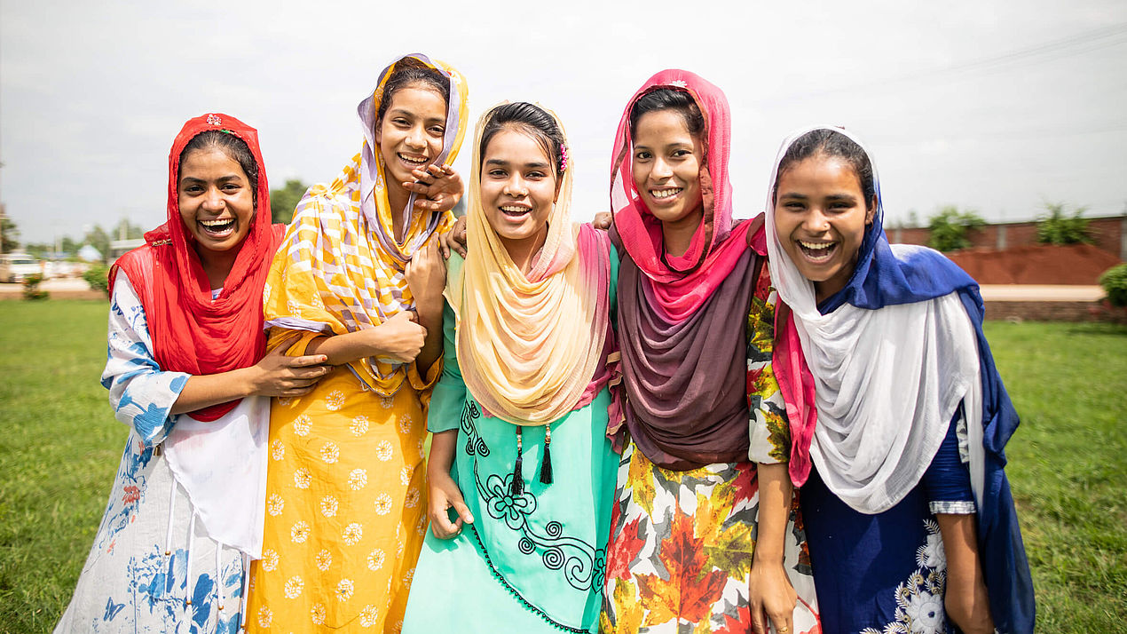 Fünf Frauen aus Bangladesch Fünf Frauen aus Bangladesch stehen Arm in Arm nebeneinander und lächeln