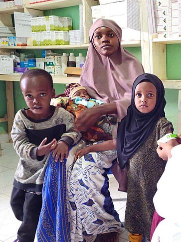 Khadra mit drei ihrer Kinder und einer Hebamme in einem Gesundheitszentrum.