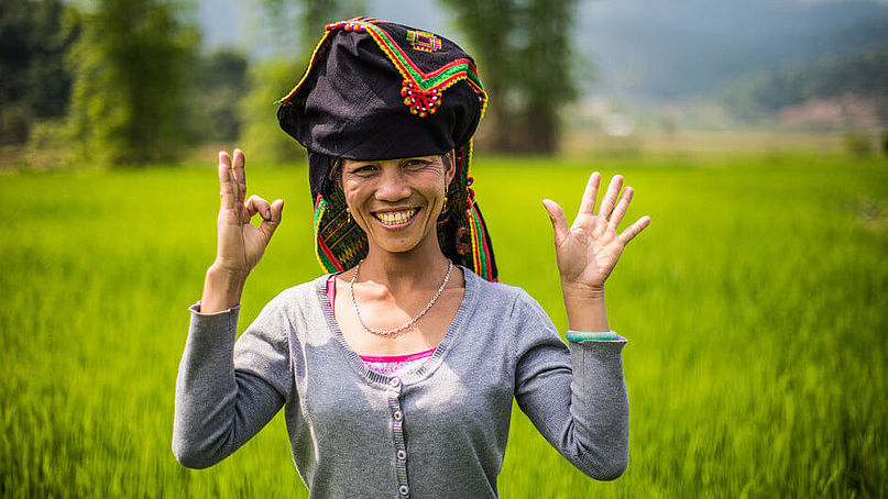 Klimaheldin Qaung Thi Klien aus Vietnam steht im Feld und macht mit ihren Händen das 1,5-Prozent-Zeichen