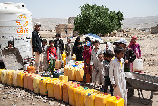 CARE Jemen: Kinder stehen vor Wasserkanistern Kinder warten vor Wasserkanistern. Im Jemen fehlt es rund 20 Millionen Menschen an sauberem Trinkwasser. CARE ist bemüht, eine Wasserversorgung für möglichst viele Menschen herzustellen. (Foto: CARE/Holly Frew)