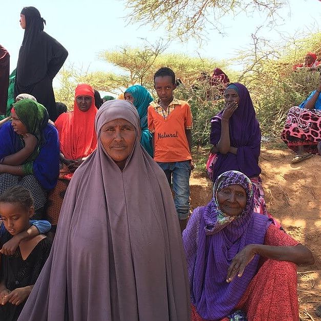 Die 50-jährige Asha aus Somalia sitzt inmitten anderer Mitglieder ihrer Gemeinde und guckt in die Kamera.