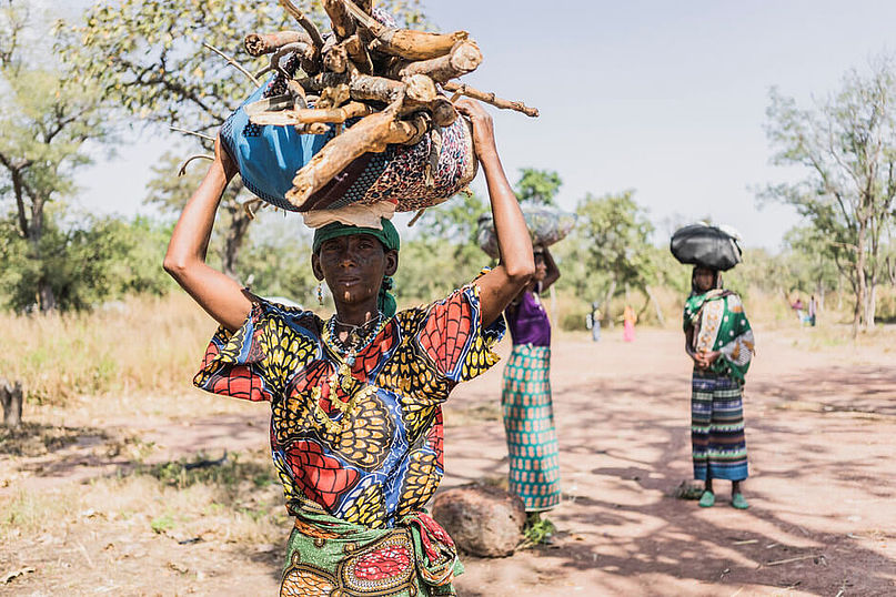 Eine geflüchtete Frau aus der zentralafrikanischen Republik trägt Holz auf ihrem Kopf
