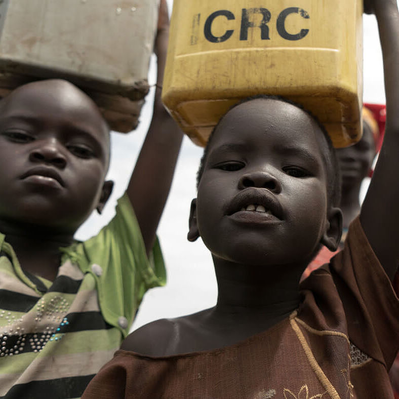 Die fünfjährige Nyahok und andere Kinder tragen Wasserkanister auf ihren Köpfen.