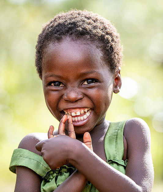 Ein Mädchen in Sambia lacht in die Kamera