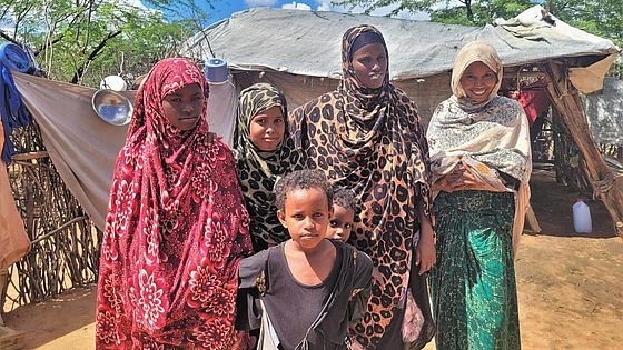 Saruro steht mit ihrer Familie im Camp in Dadaab und schaut in die Kamera.