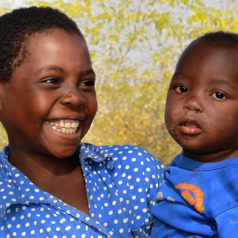 Davida aus Mosambik hält ihre kleine Schwester auf dem Arm.