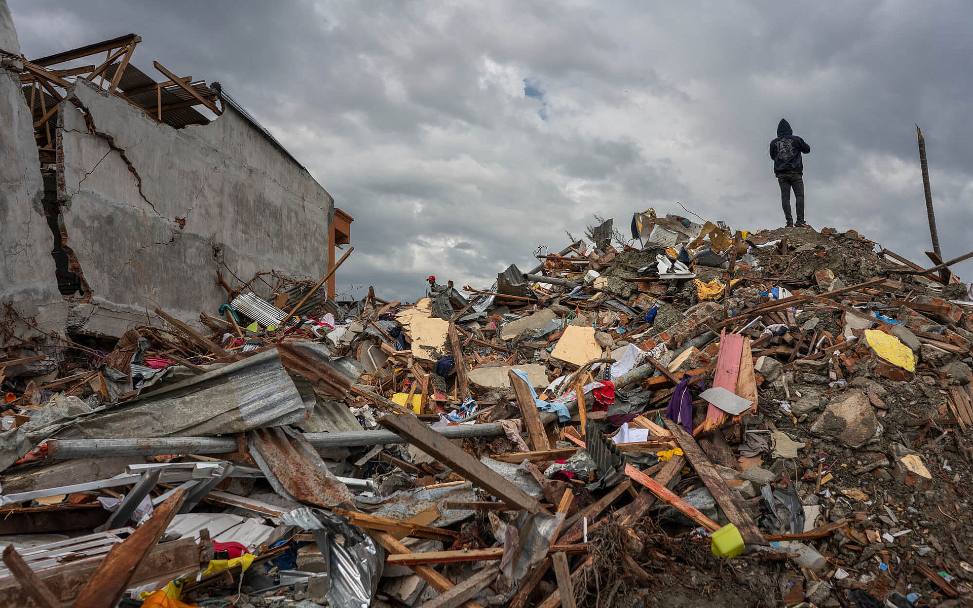 Ein Mann steht auf einem Haufen Trümmern nach dem Tsunami 2018 in Petobo Village in Indonesien
