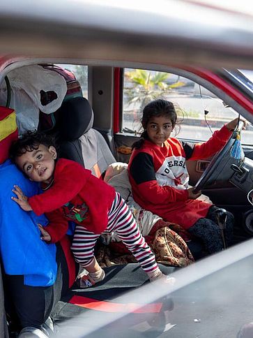 Zwei Kinder sind in einem voll beladenen Auto.