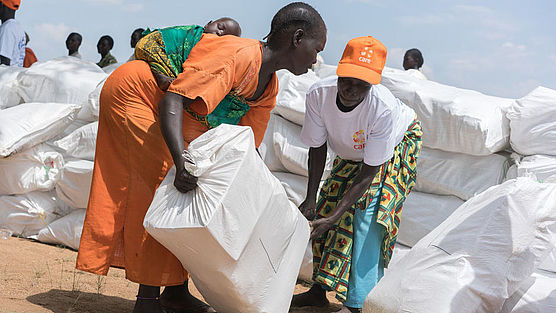 Eine CARE-Helferin gibt einer Frau in Südsudan einen Sack mit Hilfsgütern