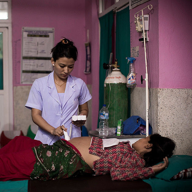 Eine schwangere Frau in Nepal in Not wird von einer Hebamme untersucht, die von CARE geschult wurde.