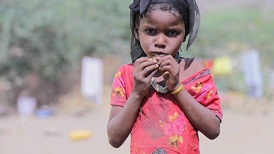 Porträt von geflüchtetem Mädchen mit Essen in den Händen.