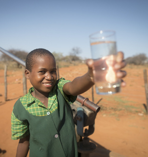 Ein lächelndes Mädchen hält ein Glas mit Wasser in der Hand