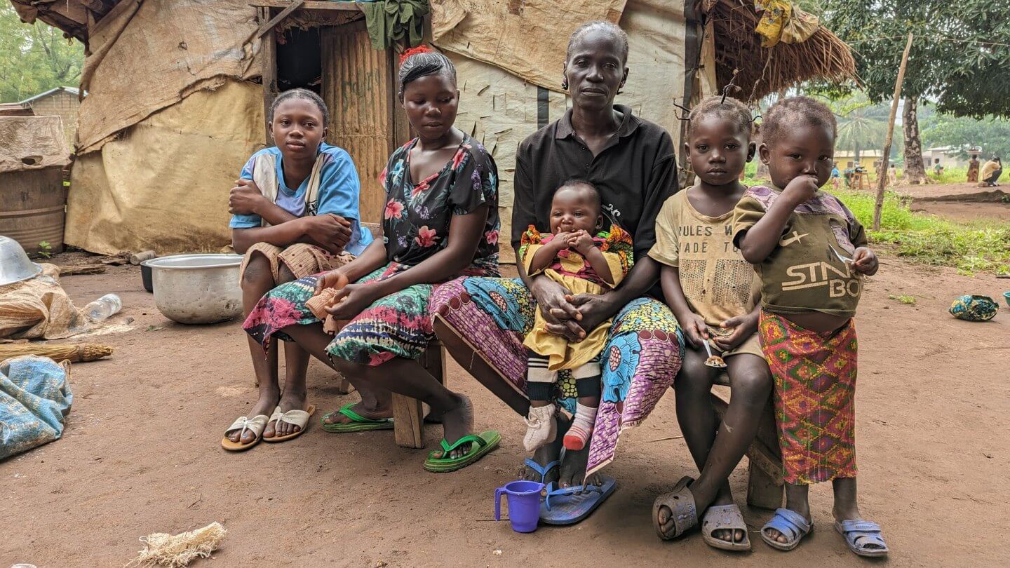 Eine Familie aus der Zentralafrikanischen Republik sitzt vor deren Hütte.