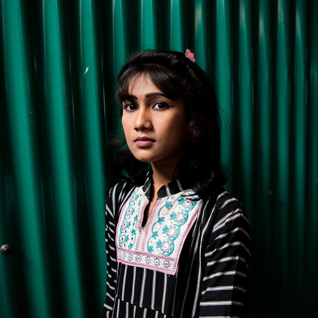 Eine junge Frau steht vor einer grünen Wand im Flüchtlingscamp