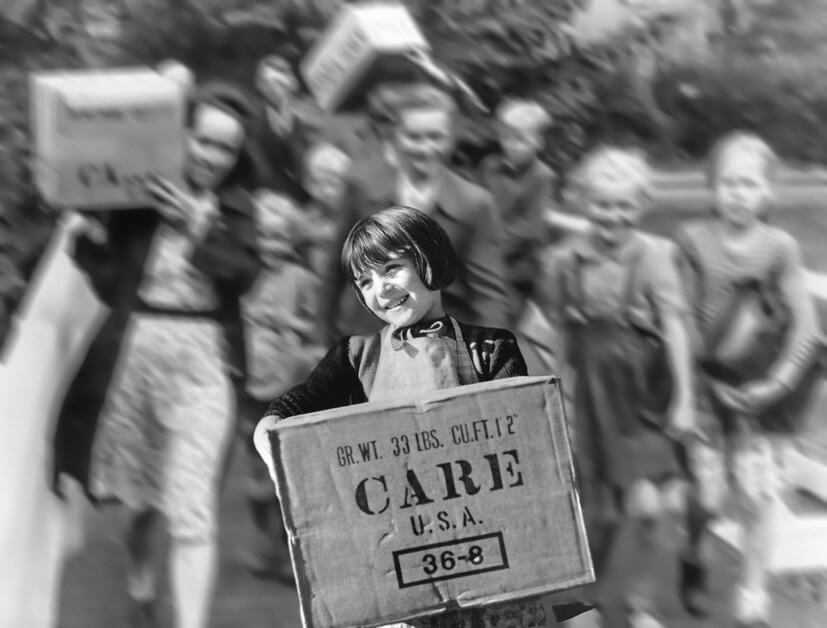 Ein schwarz-weißes Foto eines Mädchens, was ein CARE-Paket trägt