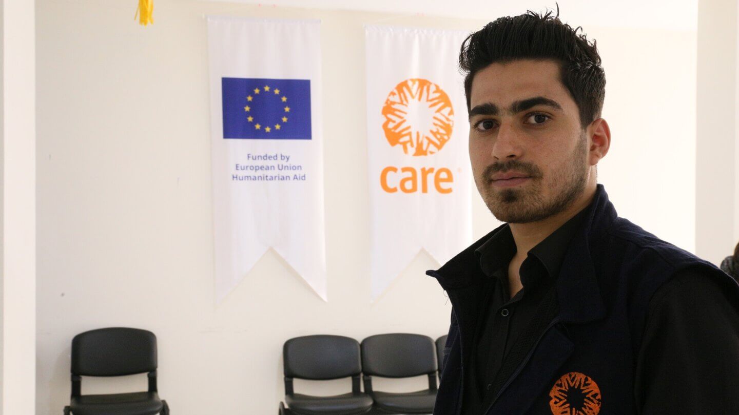 Ahmet steht vor einem CARE Logo.