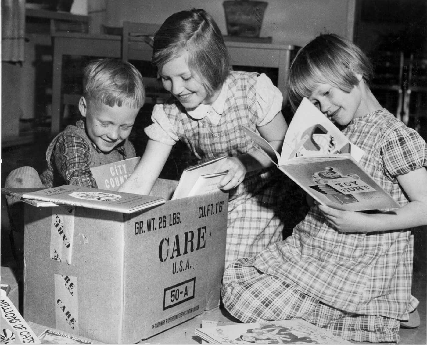 Kinder packen ein Paket aus.