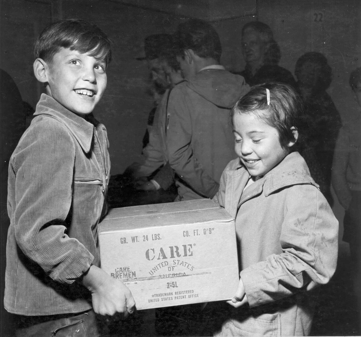 Zwei Kinder tragen ein Paket in den Händen.